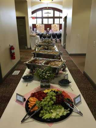 Long buffet table filled with fresh vegetables, hot food, and catering setup.
