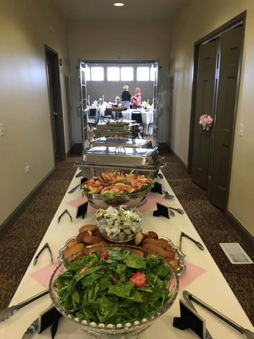 Buffet table in hallway, laden with bowls of salad, bread, and food.