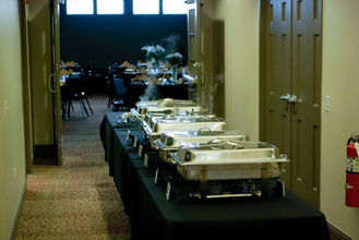 Buffet table with steaming chafing dishes set up for an event.