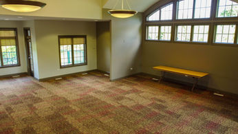 Empty room with patterned carpet, large arched window, and wooden bench.