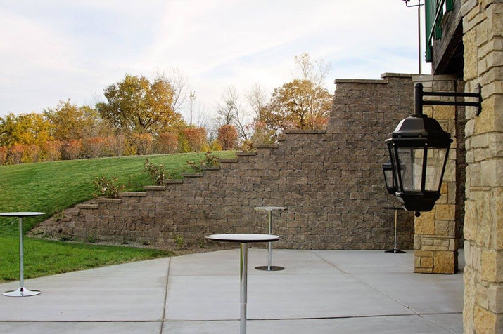 Outdoor patio with cocktail tables, stone wall, and autumn trees.