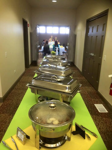 Buffet table with silver chafing dishes in a hallway for event catering.