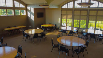Spacious meeting room with round tables, chairs, and large windows.