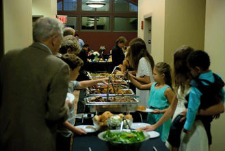 Many guests serving themselves diverse food from a large buffet line.