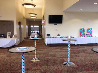 Large event room with buffet food, cocktail tables, and EXIT sign.