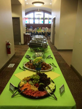Long buffet table spread with various dishes on a green tablecloth.