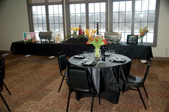 Event room with black tables, orange tulips, buffet, and winter view.