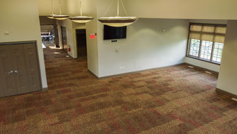 Spacious empty room with patterned carpet, large window, and modern lights.